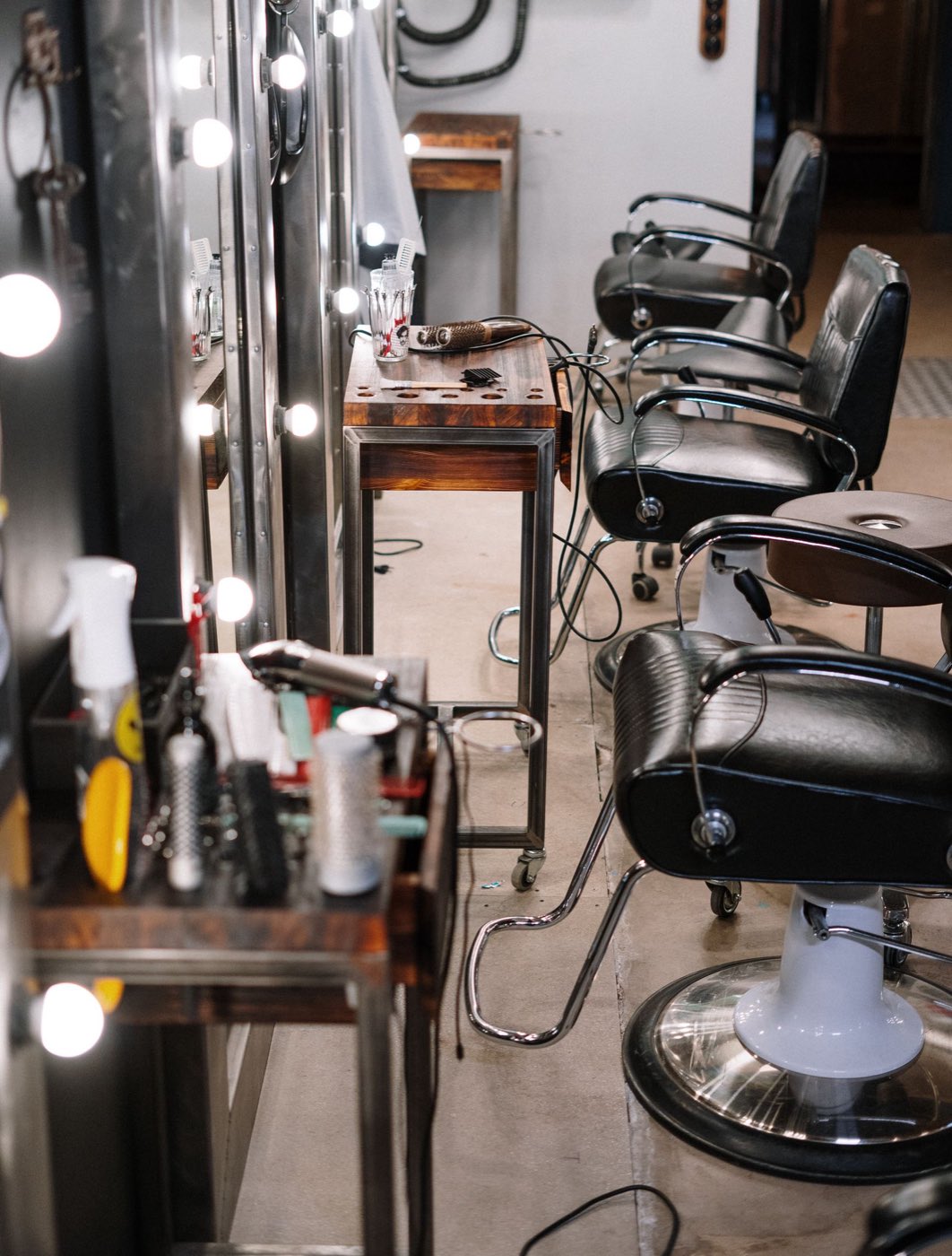 An empty black leather barber chair in front of a mirror